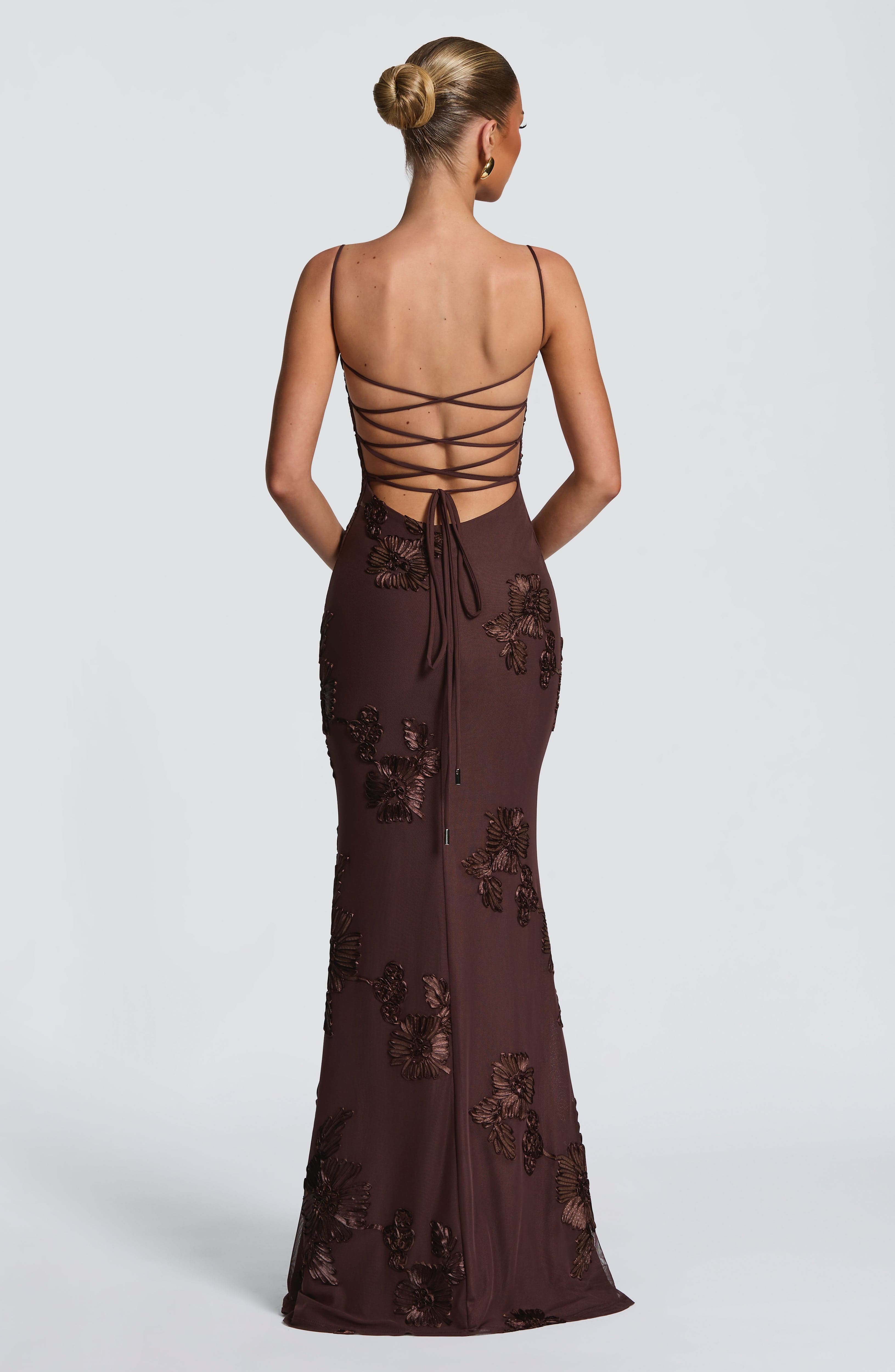 Back view of a brown floral maxi dress with delicate spaghetti straps and lace-up detailing, suitable for ladies evening gowns.