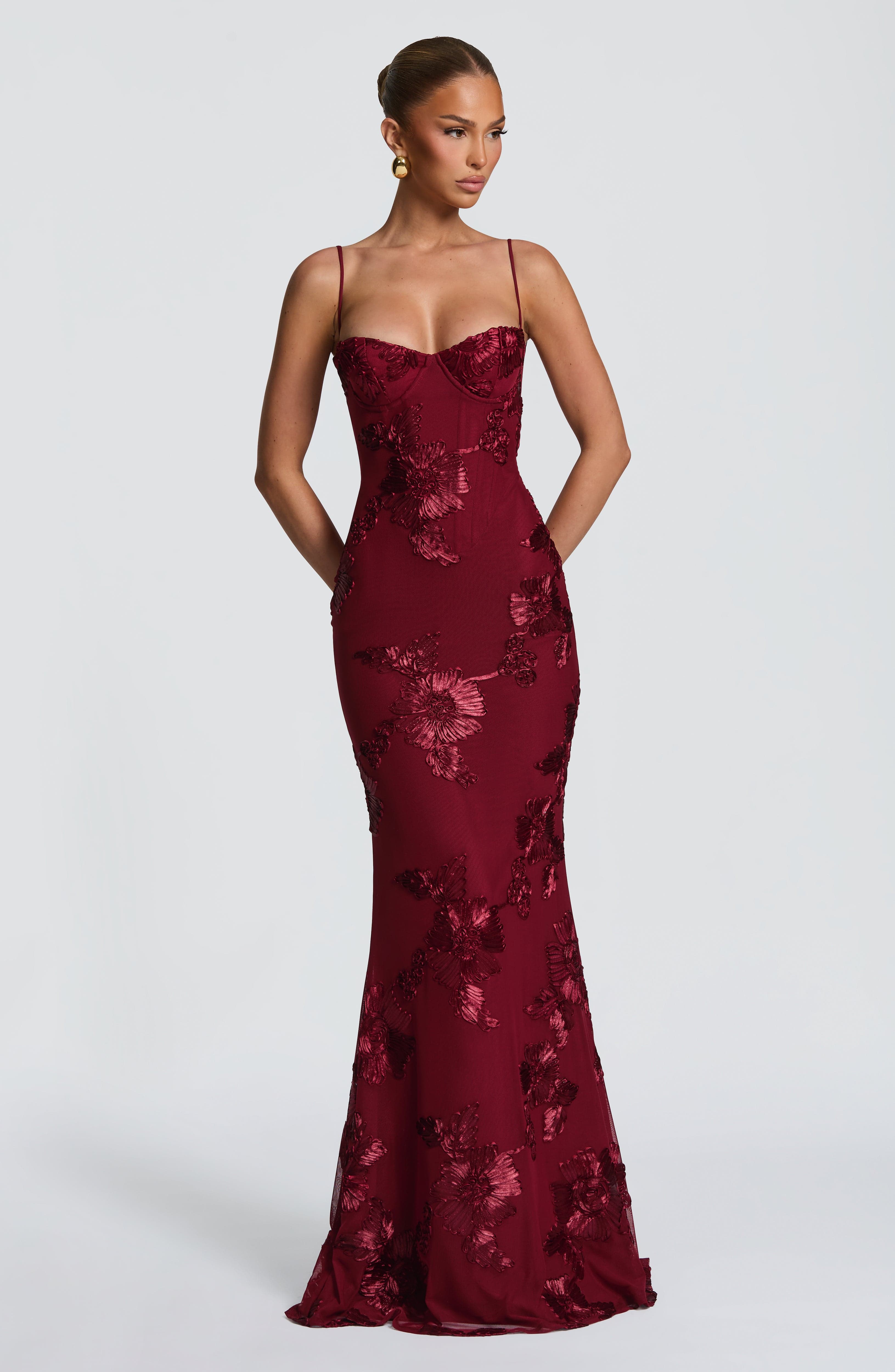 Front view of a deep red floral maxi dress with delicate spaghetti straps and a fitted silhouette, ideal for ladies evening gowns.