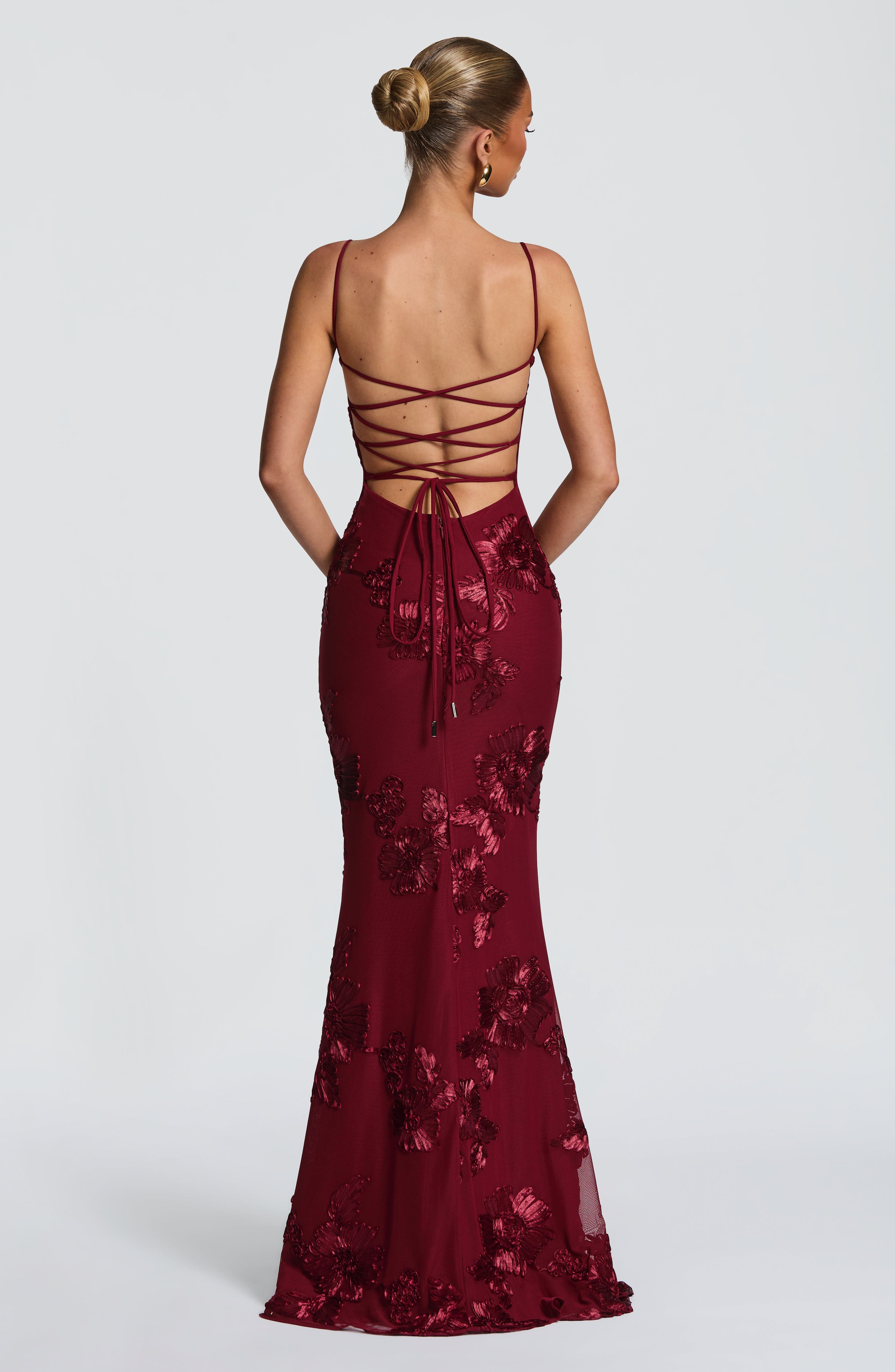 Back view of a deep red floral maxi dress featuring a criss-cross lace-up back and intricate floral embroidery, perfect for formal clothes.