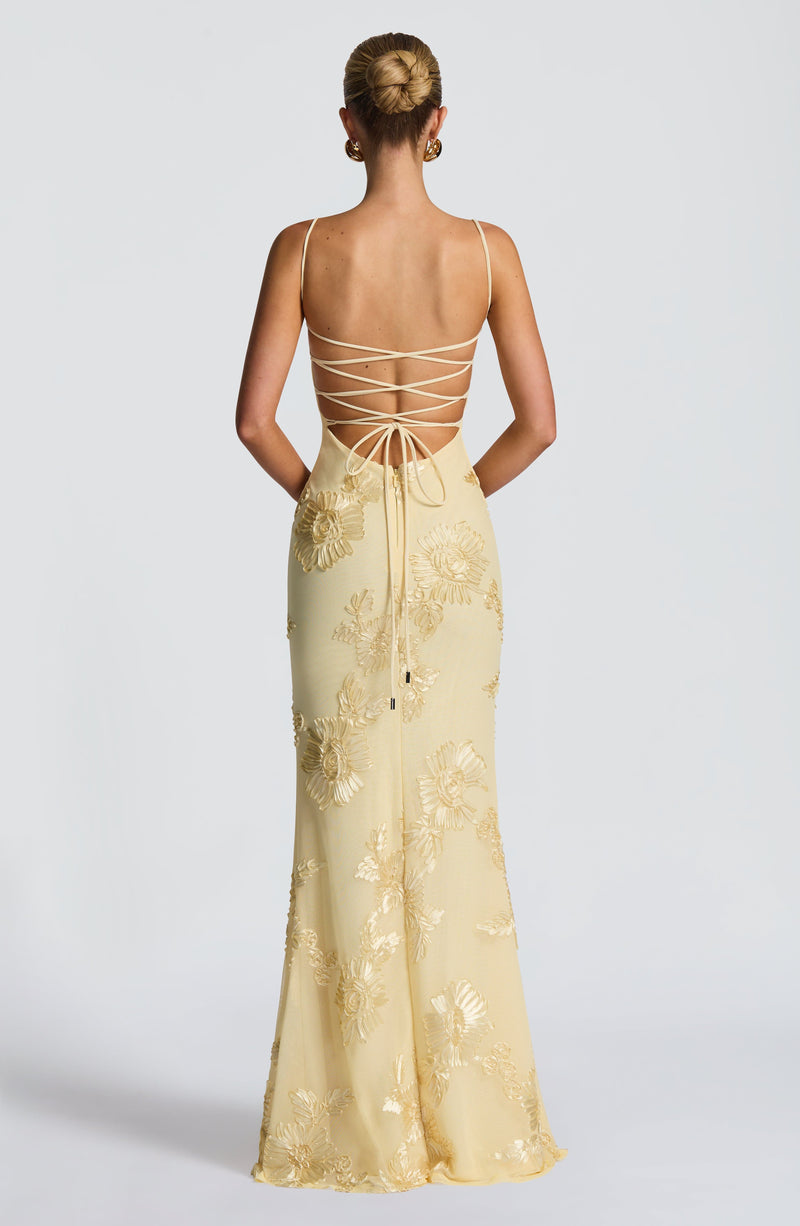 Back view of the light yellow Celestina floral maxi dress, showcasing the lace-up detail and gold floral embroidery on the skirt.