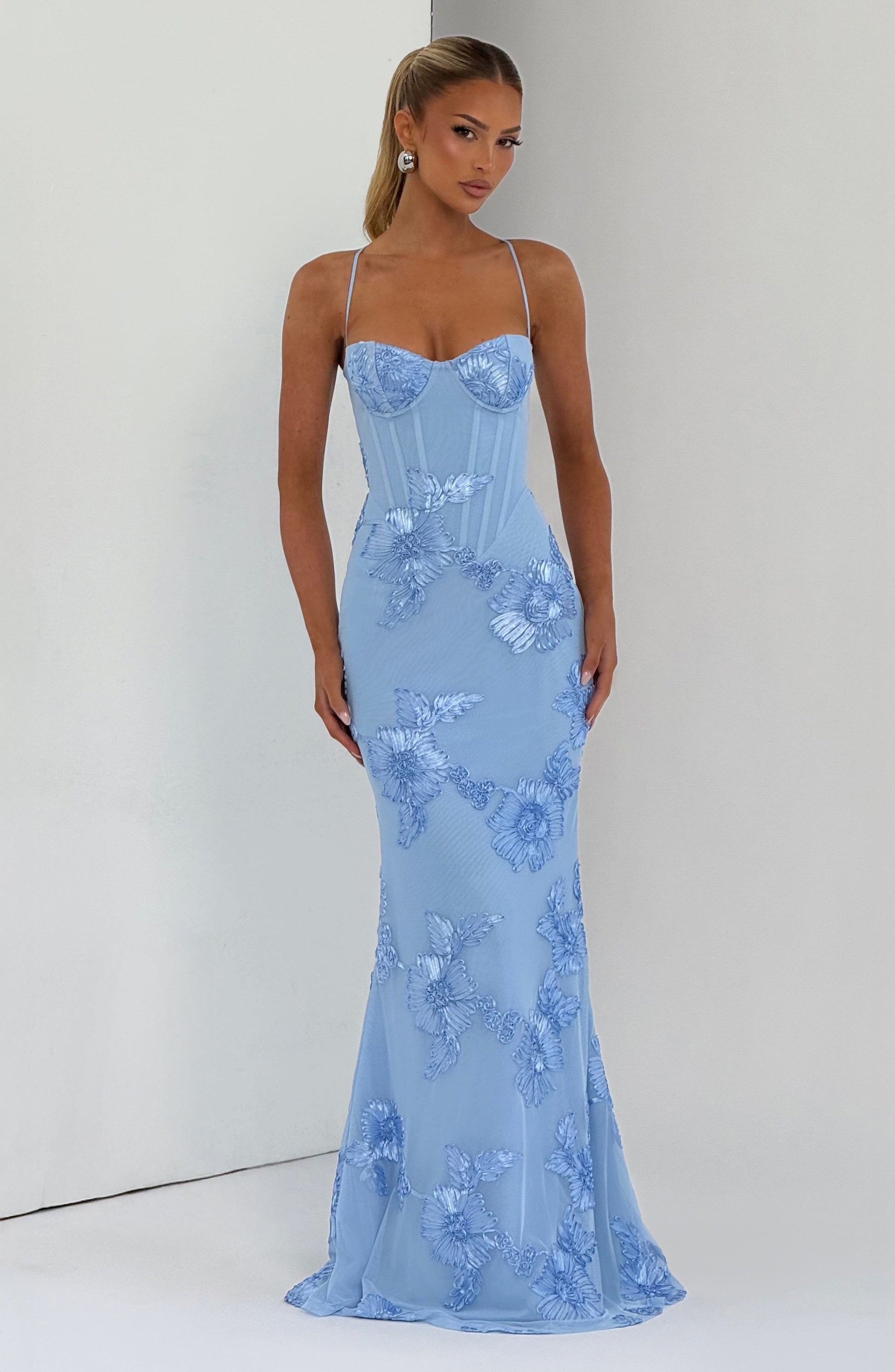Full-length view of a light blue floral maxi dress with a subtle train, delicate straps, and a fitted silhouette, showcasing the detailed floral embroidery.