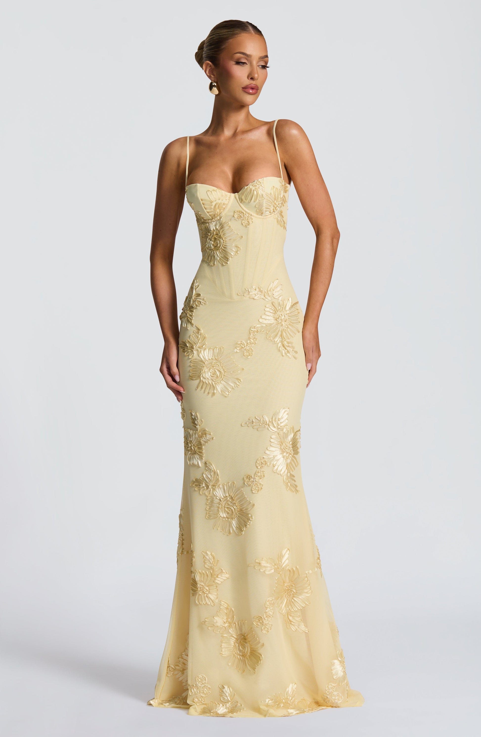 Front view of a woman in the light yellow Celestina floral maxi dress, displaying the sweetheart neckline and intricate gold floral embroidery on the bodice and skirt.