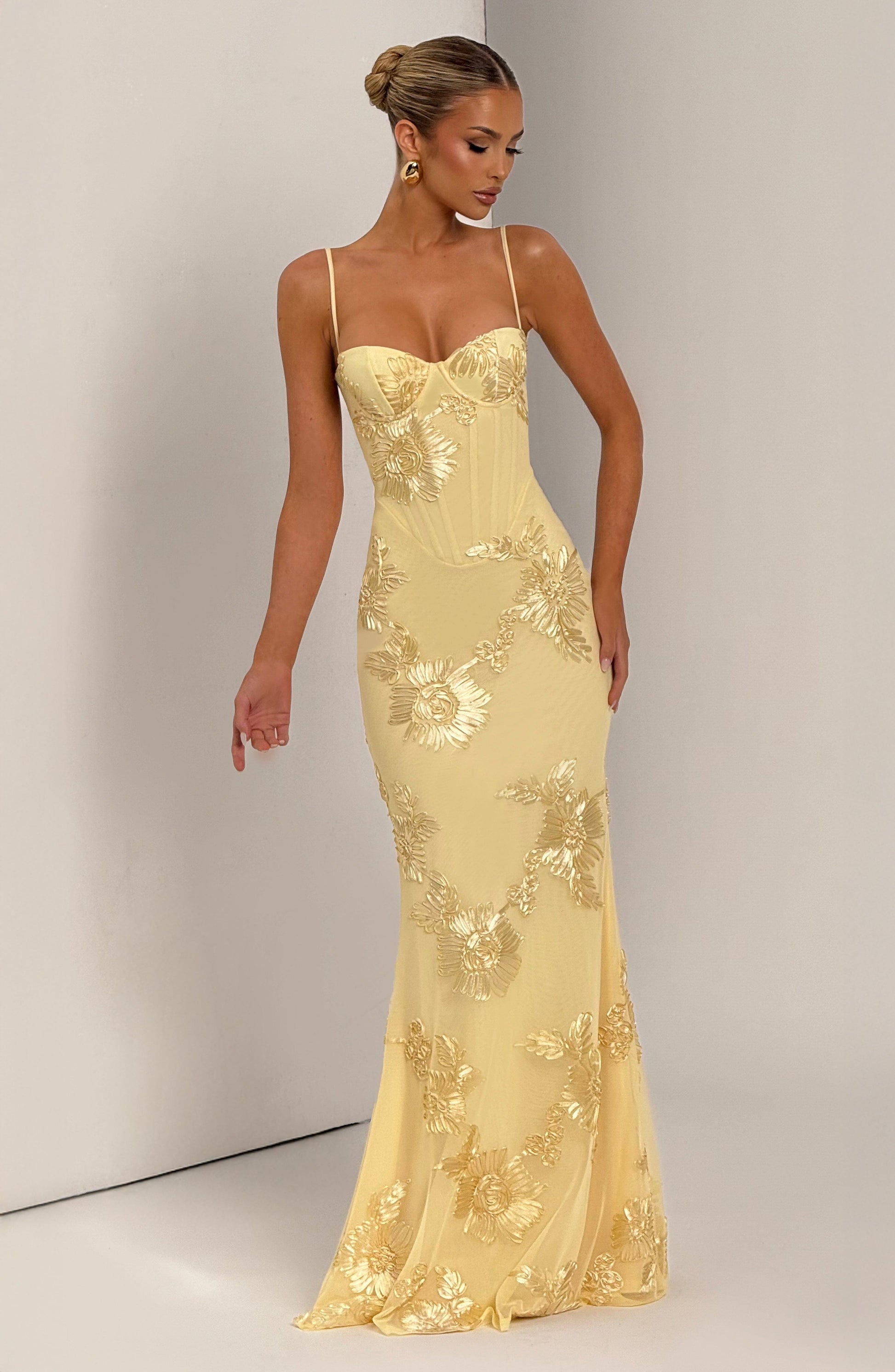 Woman standing gracefully in the light yellow Celestina floral maxi dress, showcasing the full length and delicate gold floral details.