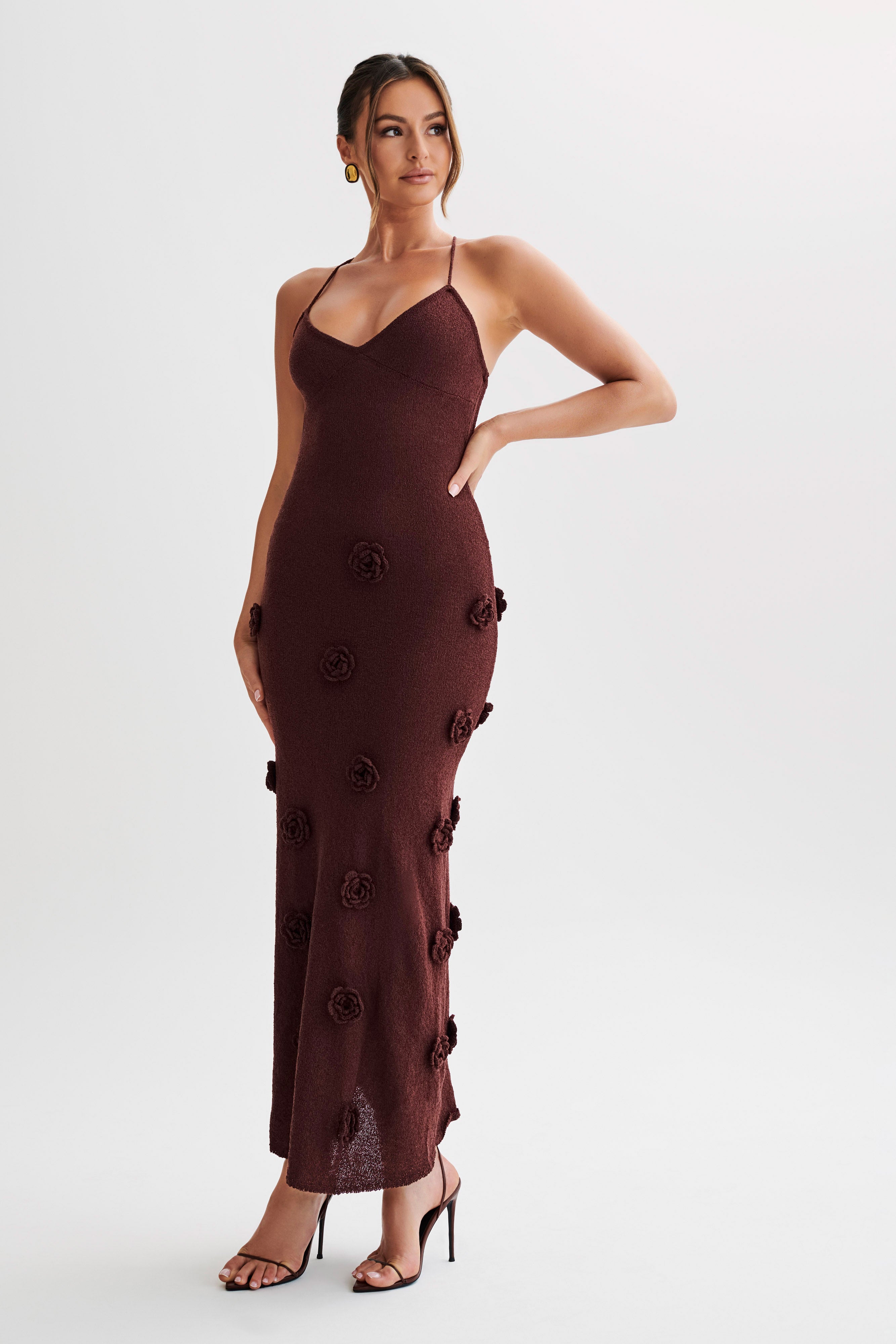 Three-quarter view of the dark brown Chelsea Floral Maxi Dress, featuring a subtle shimmer and elegant floral appliques down the length.