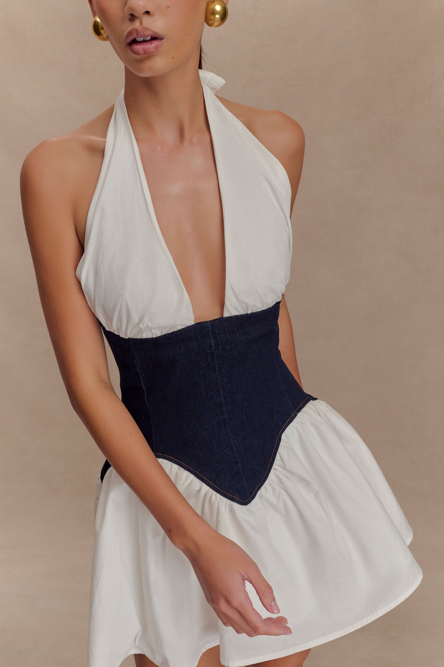 Close-up front view of the Christina mini dress, highlighting the white halter neckline, dark denim corset, and white ruffled skirt.