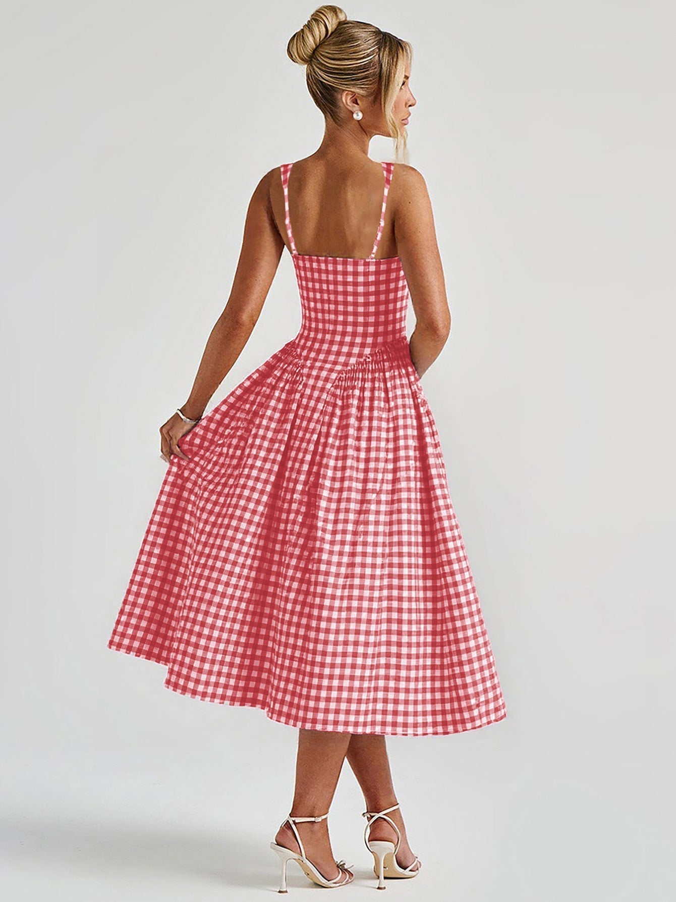 Back view of a red and white gingham midi dress with delicate spaghetti straps and a full, gathered skirt, worn with white heels.