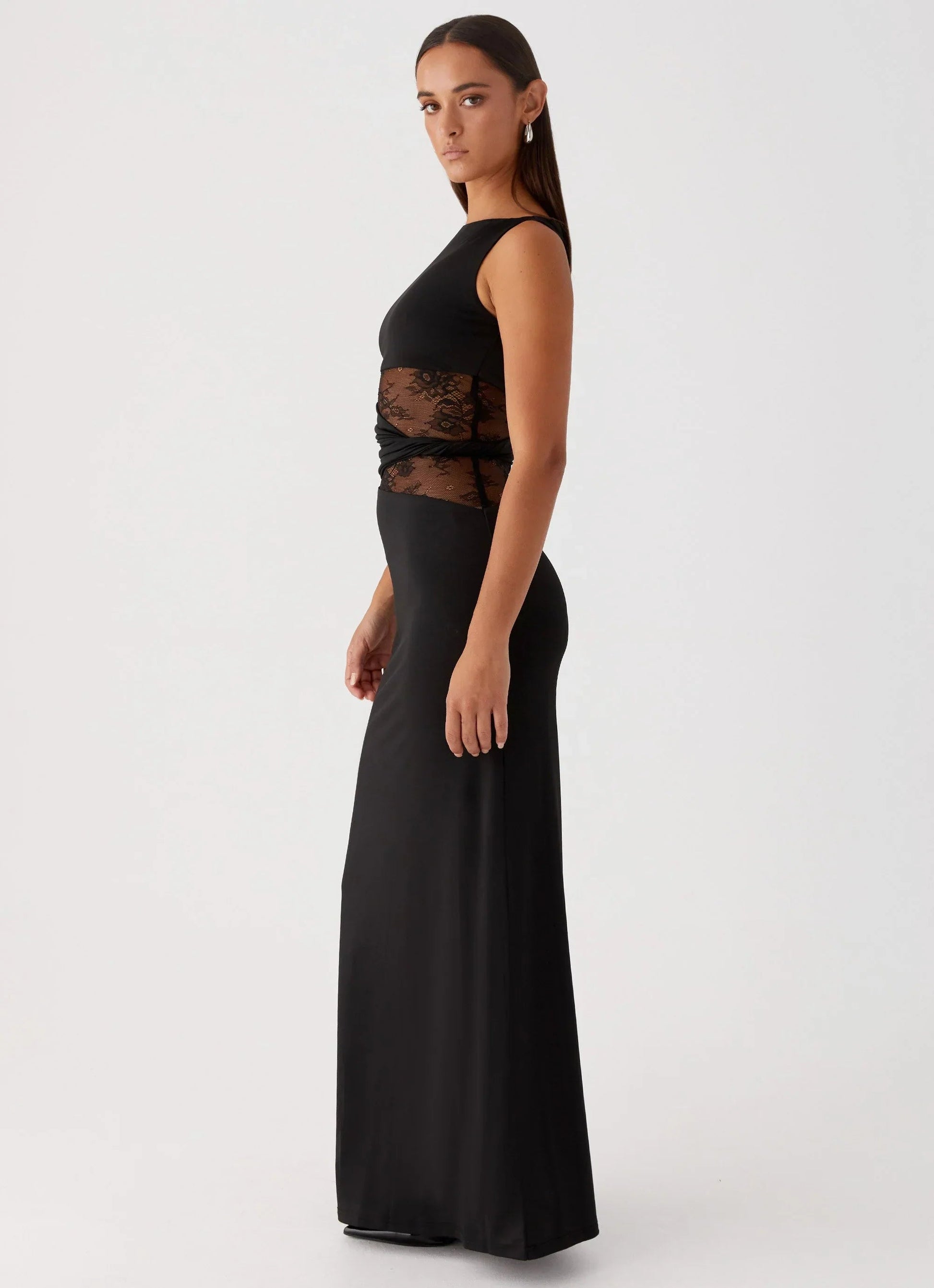 Side profile of the black Clarisse maxi dress, showcasing the sleeveless design and lace waist panel.