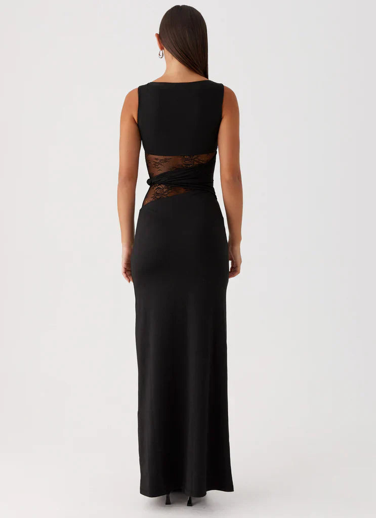 Rear view of the black Clarisse maxi dress, showing the boat neck and back lace cutouts at the waist.