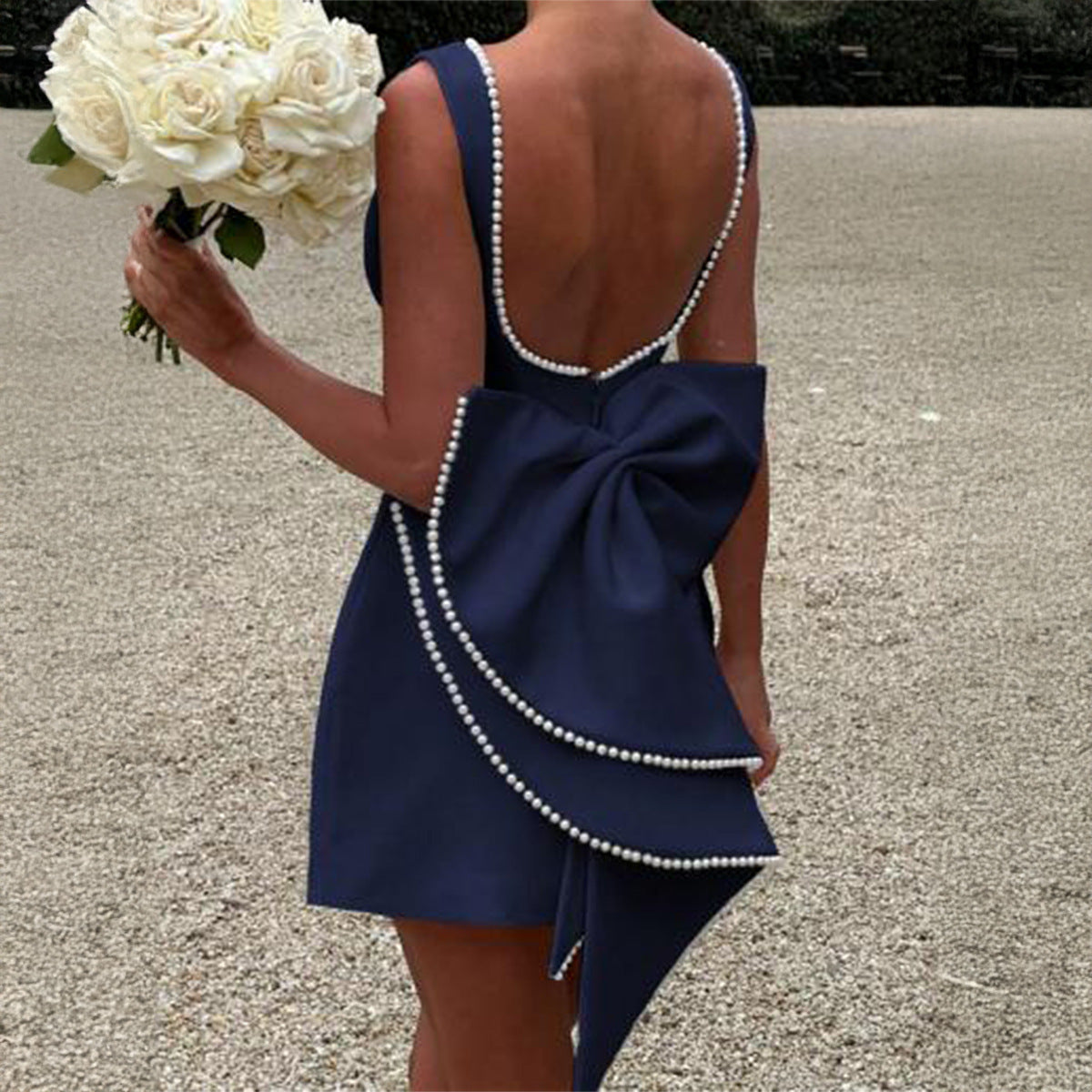 Navy blue mini dress from behind, showcasing a large pearl-trimmed bow and a low back with pearl detailing.