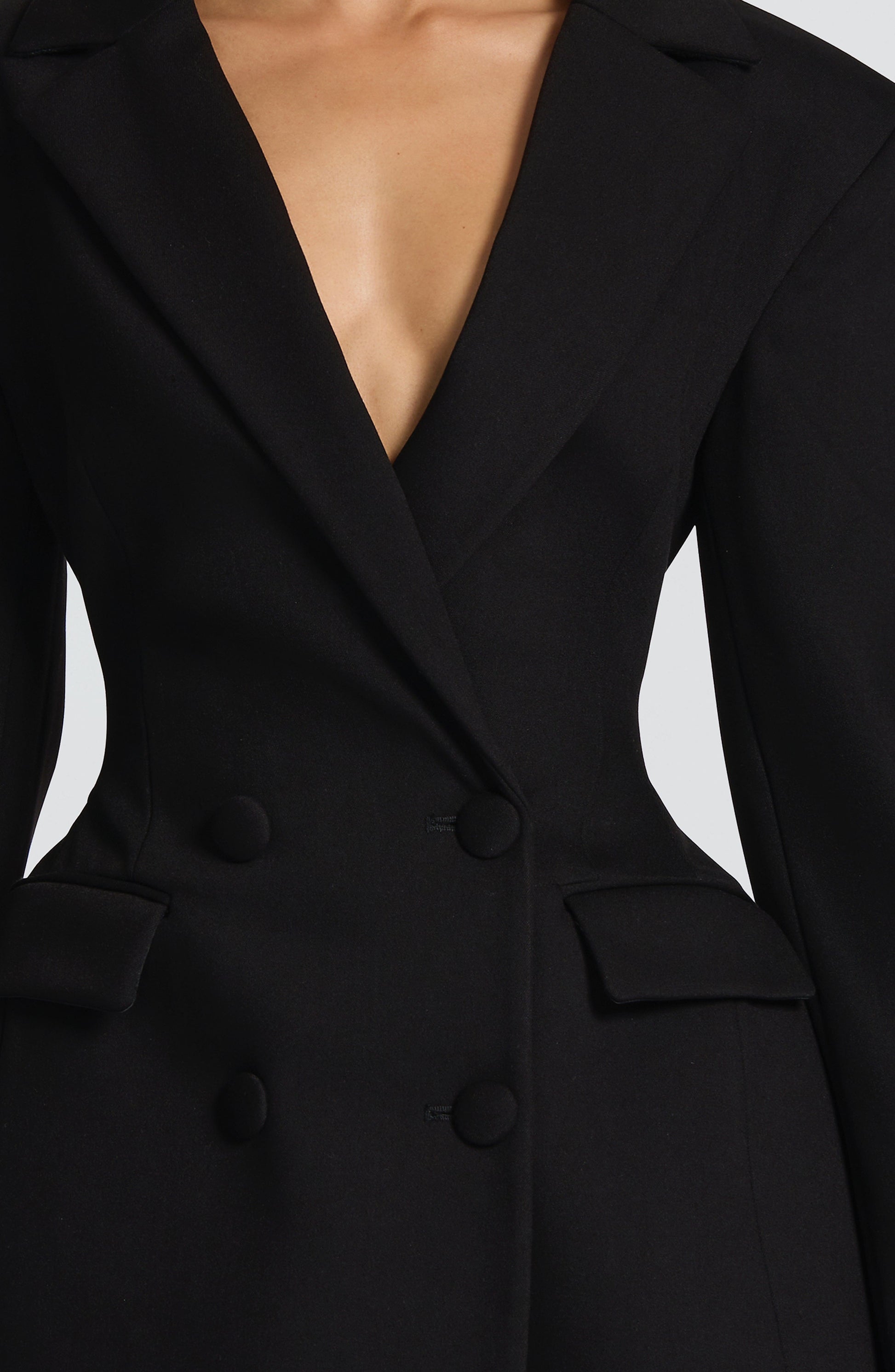 Close-up of the black double-breasted blazer mini dress, detailing the buttons and lapel design.