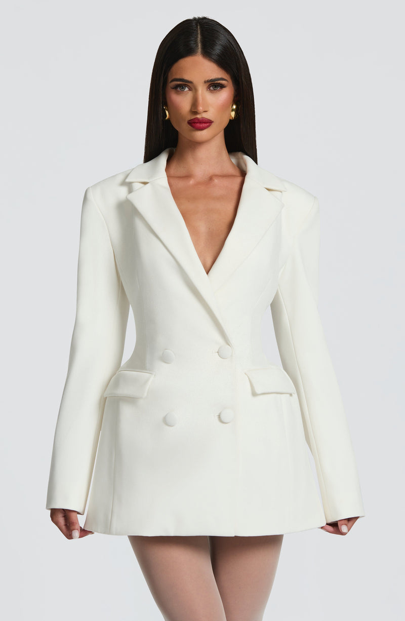 Front view of a white double-breasted blazer mini dress with peak lapels and two rows of buttons.
