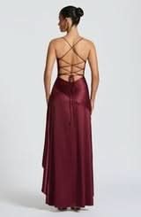 Back view of a deep burgundy satin maxi dress, showcasing the intricate criss-cross lace-up back design and flowing skirt.