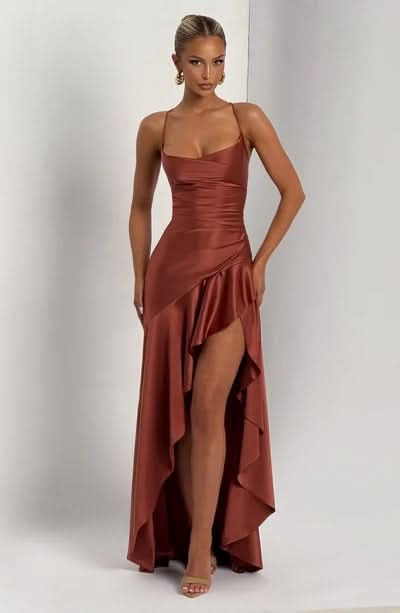 Full-length front view of a rust-colored satin maxi dress featuring a high-low ruffled skirt and spaghetti straps.