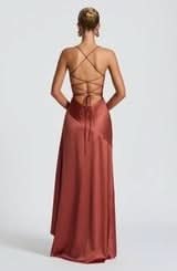 Rear view of the rust-colored satin maxi dress, highlighting the intricate lace-up back and elegant drape.