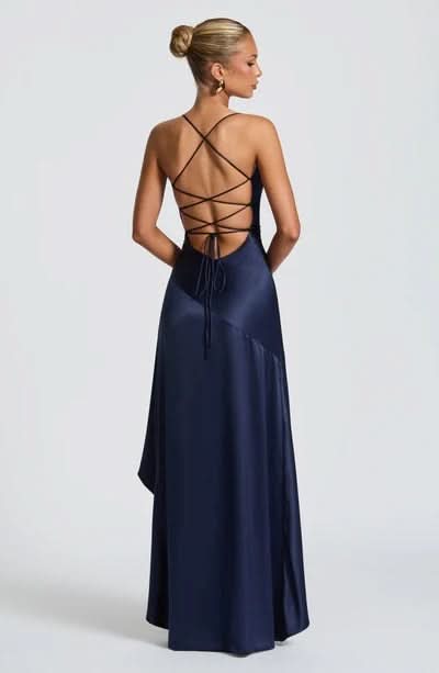 Back view of a navy blue maxi dress with criss-cross lace-up back detail and a flowing skirt.