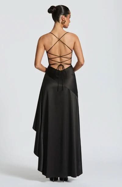 Back view of a black maxi dress featuring a multi-strap lace-up design and a subtly ruffled skirt.