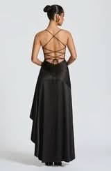 Rear view of a black maxi dress showcasing the lace-up back closure and a flowing, asymmetrical skirt.