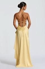 Back view of a light yellow maxi dress featuring delicate criss-cross lacing and a flowing ruffled skirt.