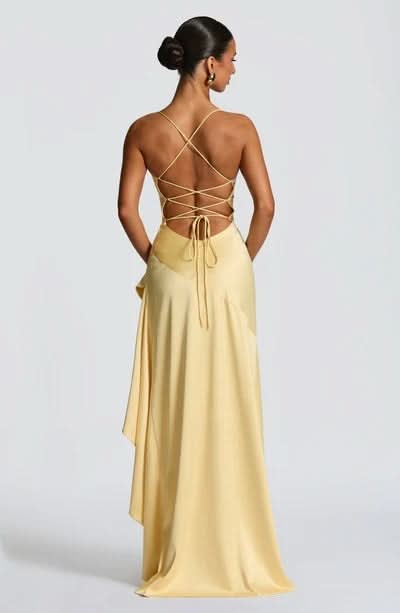Rear view of a yellow Daisy Ruffle Maxi Dress, showcasing the intricate lace-up back and draped ruffle detail.