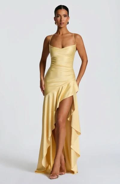 Full body view of a light yellow Daisy Ruffle Maxi Dress with a draped bodice and asymmetrical ruffled skirt.