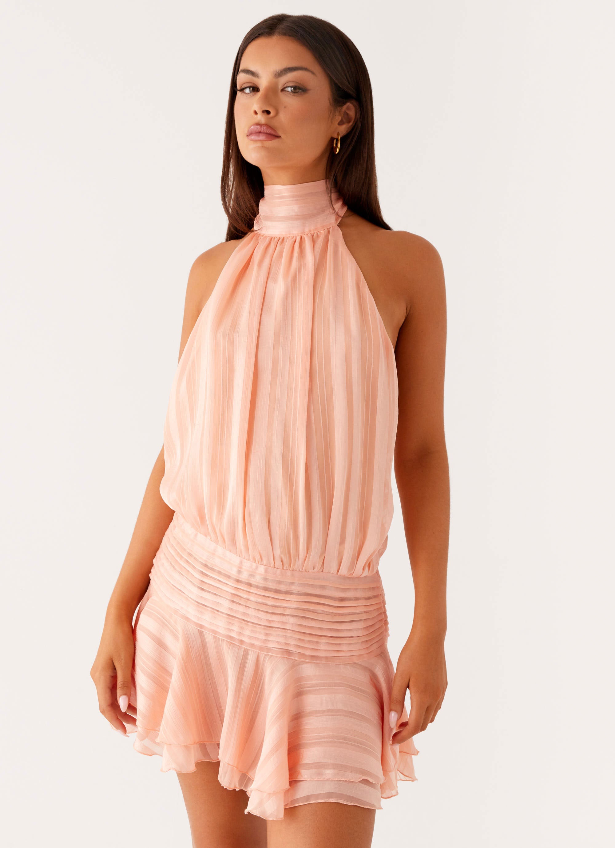 Soft pink Daniela pleated mini dress with a halter neck, shirred bodice, and a flared, pleated skirt.