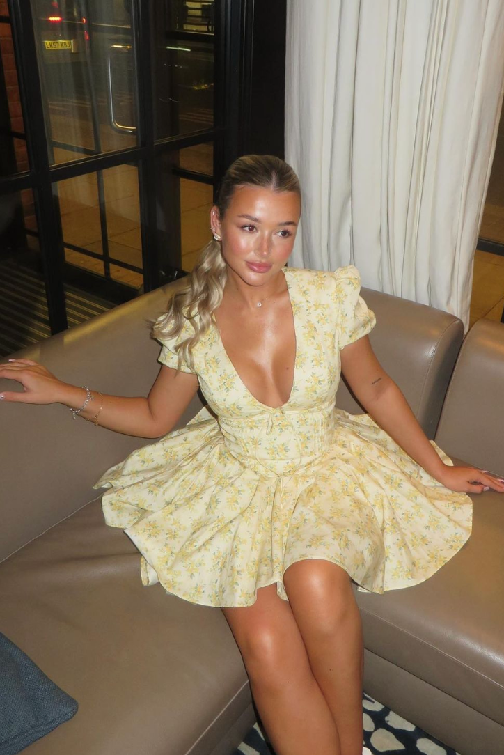 Delaney pleated mini dress in light yellow with small floral print, featuring a deep V-neck and gathered short sleeves.
