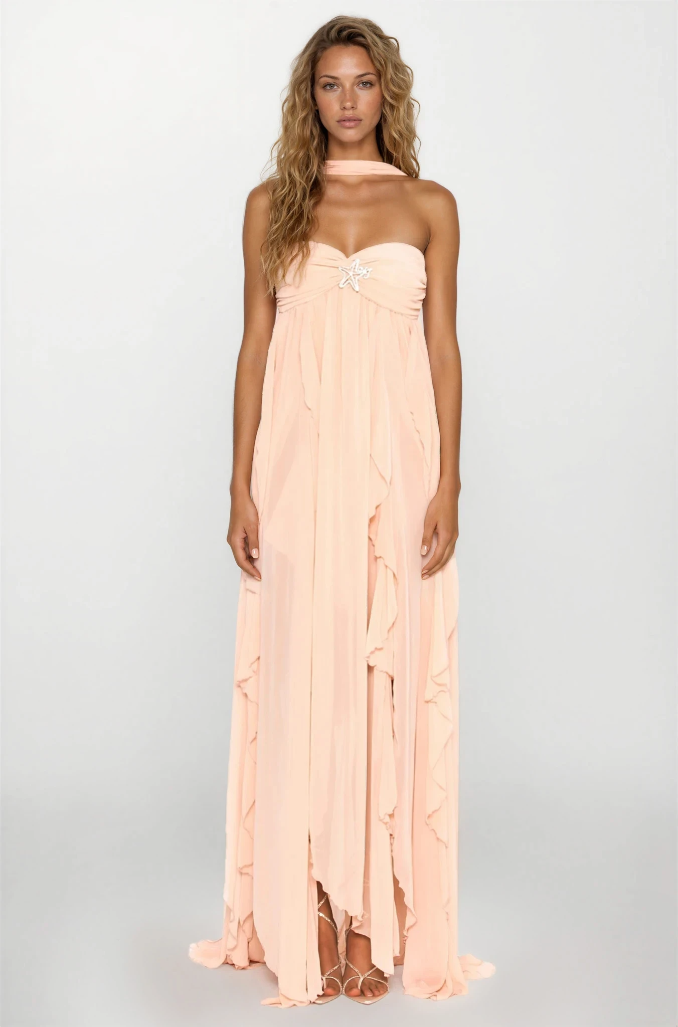 Full view of Elaina peach ruched maxi dress with halter ties, star jewel, and ruffled skirt on model