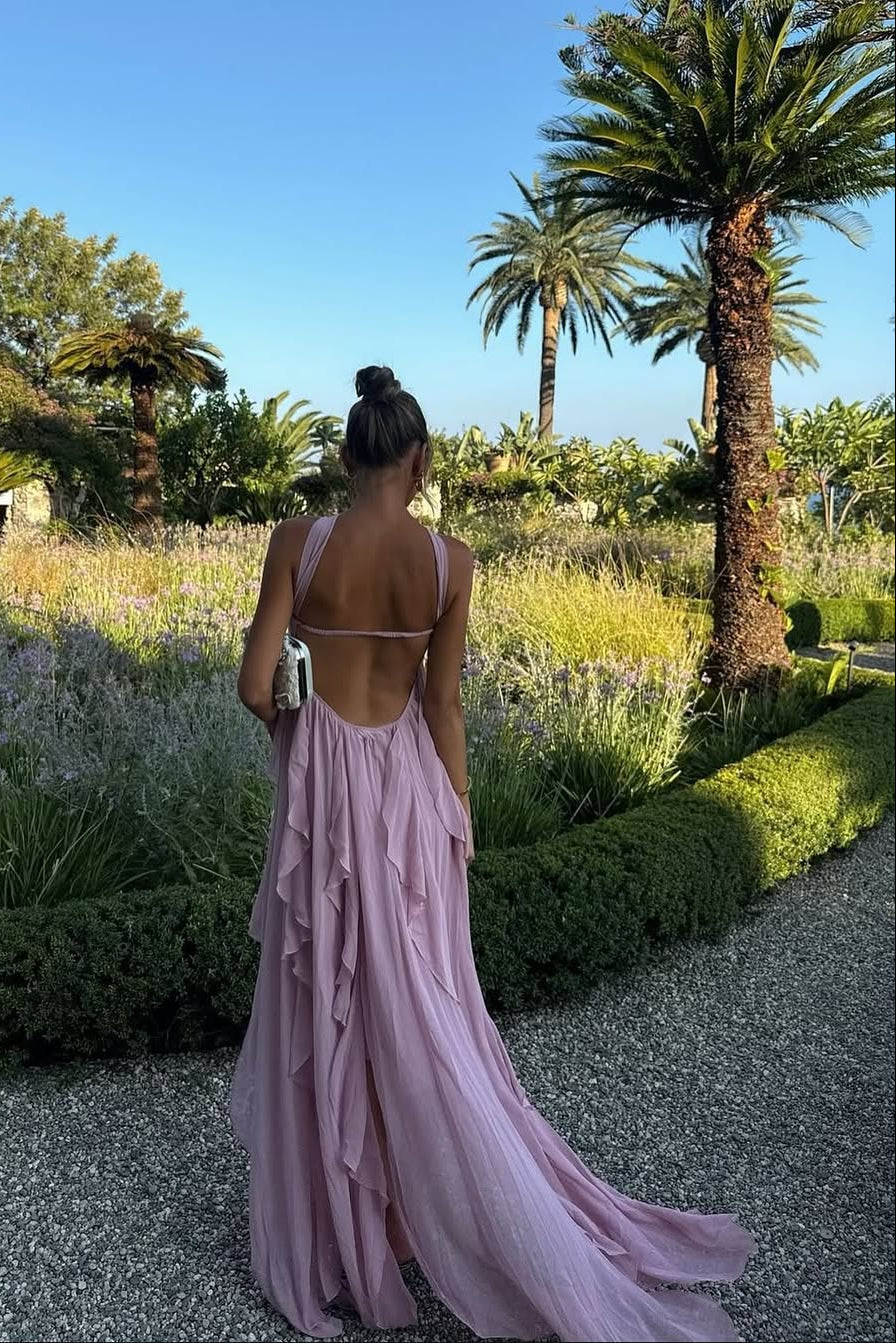 Back view of a light pink ruched maxi dress with an open back and long flowing skirt with ruffles, seen from behind.