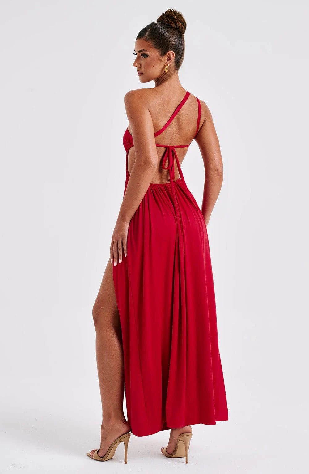 Back view of red Elara Ruched Maxi Dress, featuring an open back with tie detail and high leg slit.