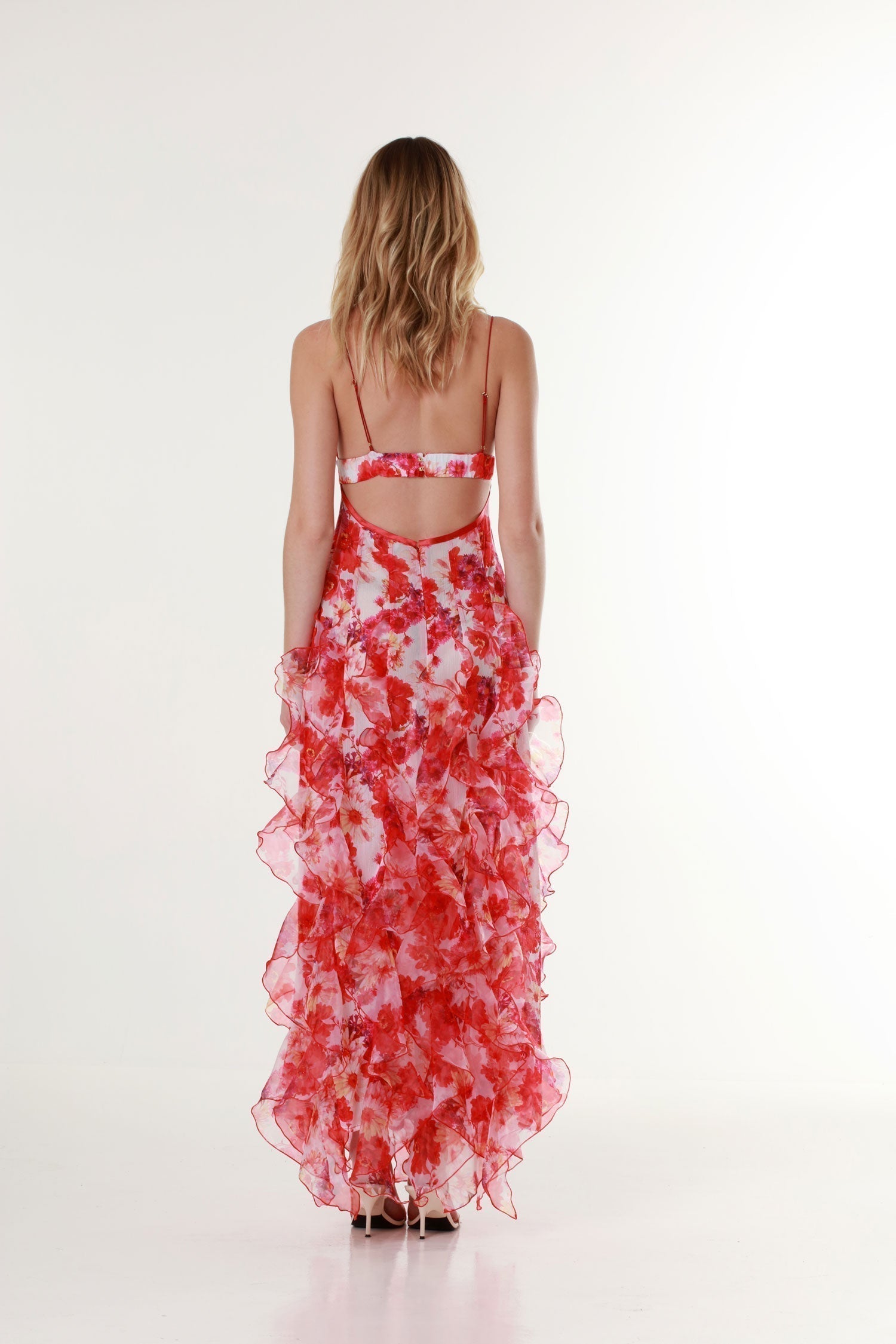 Back view of a red and pink floral print ruffle maxi dress with thin spaghetti straps
