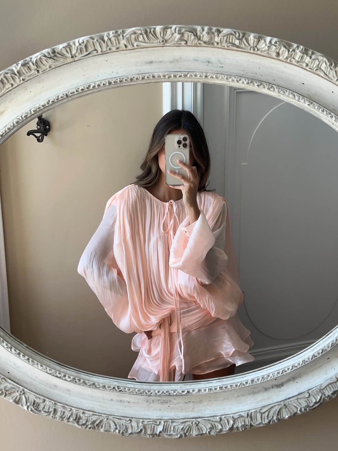 Selfie view of the light pink Elianna shirred mini dress, showcasing the shirred bodice and tie-neck detail in a mirror.
