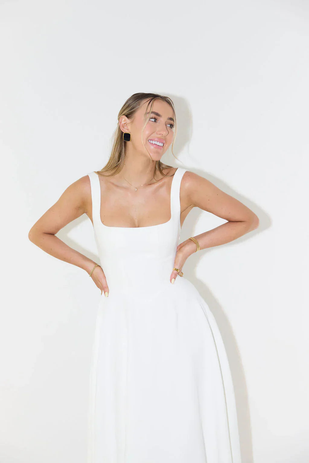 Smiling model in the Eliza A-line midi dress in white, with hands on hips, showcasing the square neckline and fitted bodice.