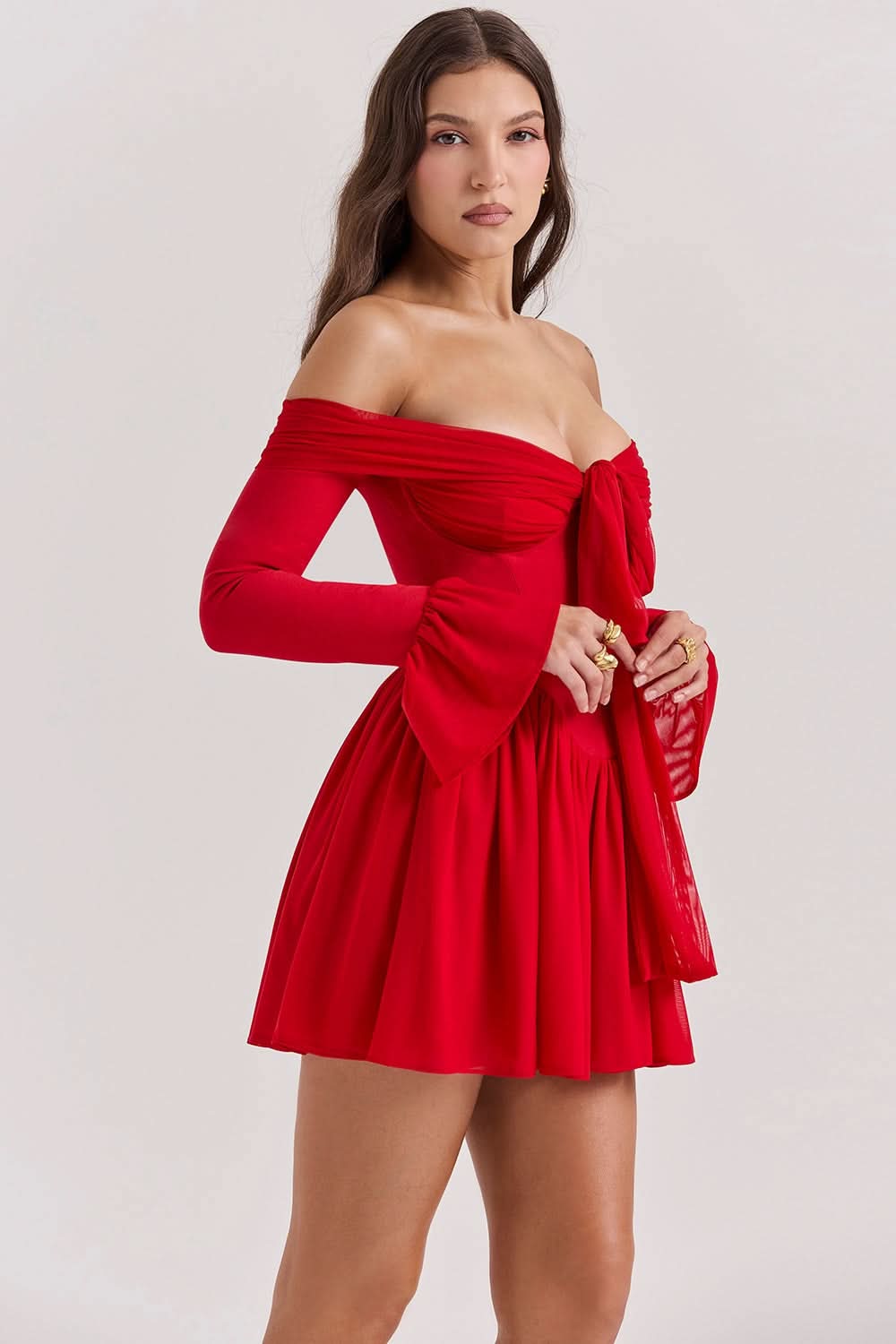 Angled view of a vibrant red Elsie Bow Mini Dress with off-the-shoulder sleeves, a fitted bodice, and a pleated skirt.