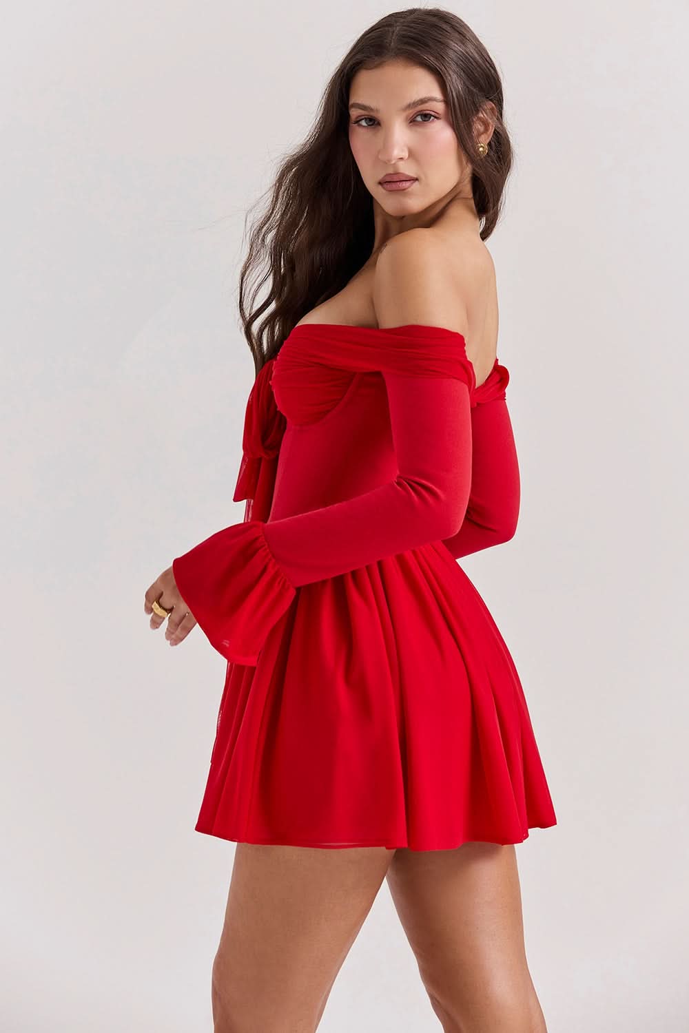 Side profile of the red Elsie Bow Mini Dress, highlighting the gathered off-shoulder neckline and bell sleeves with a flowing skirt.