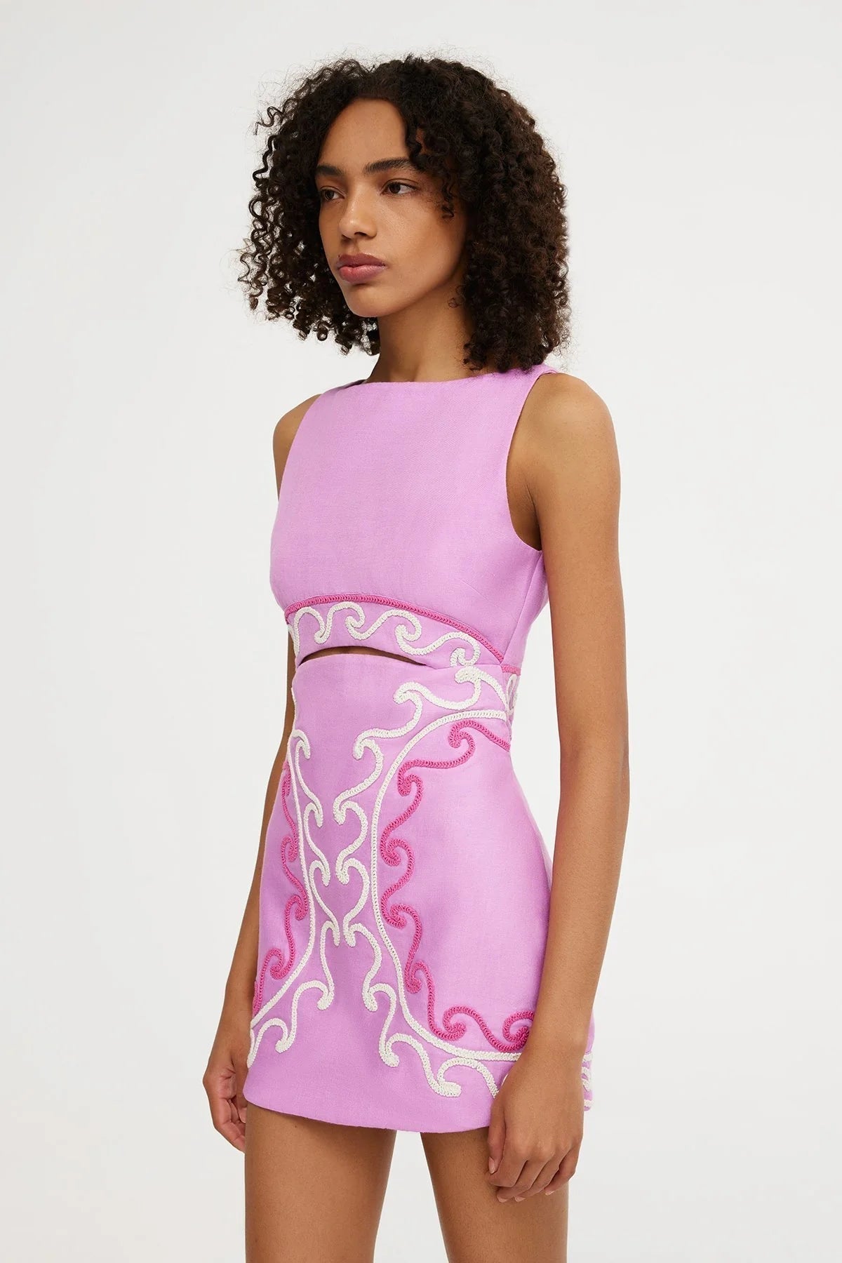 Side profile of pink embroidered mini dress with intricate white and pink patterns for women.