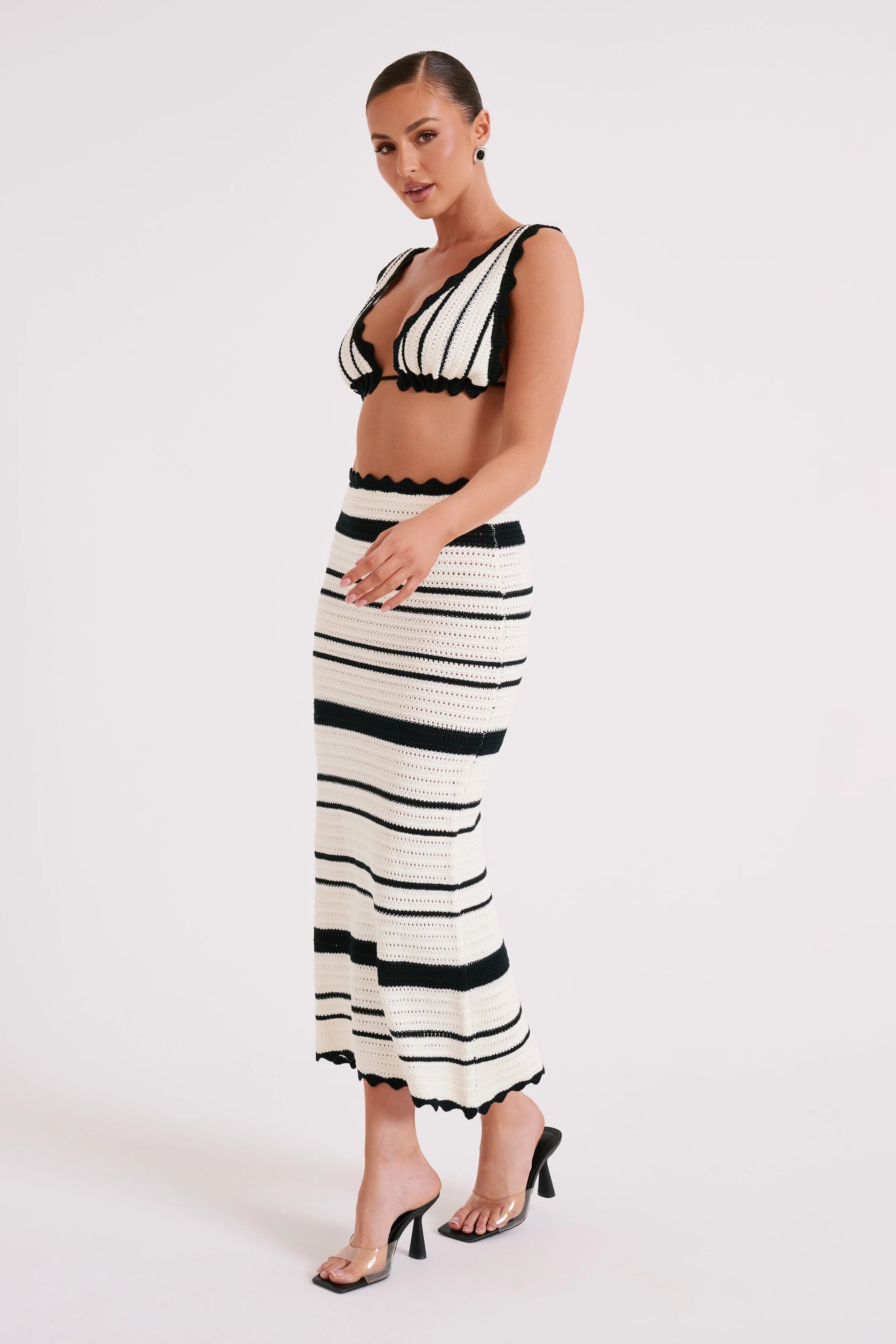 Side view of a white and black striped crochet maxi set, showing the bralette top and form-fitting skirt.