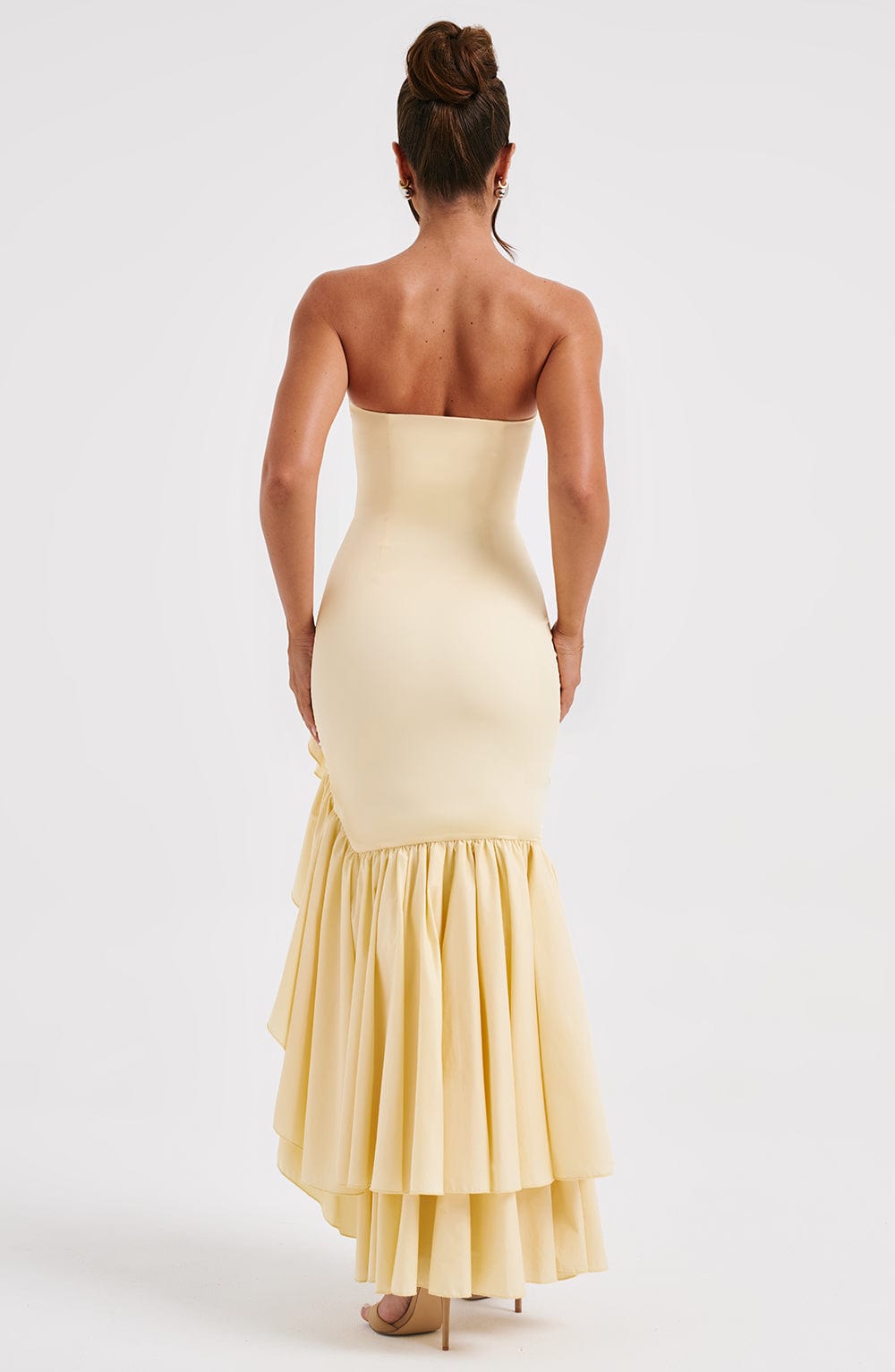 Back view of the pale yellow strapless maxi dress, highlighting the gathered ruffles on the skirt.