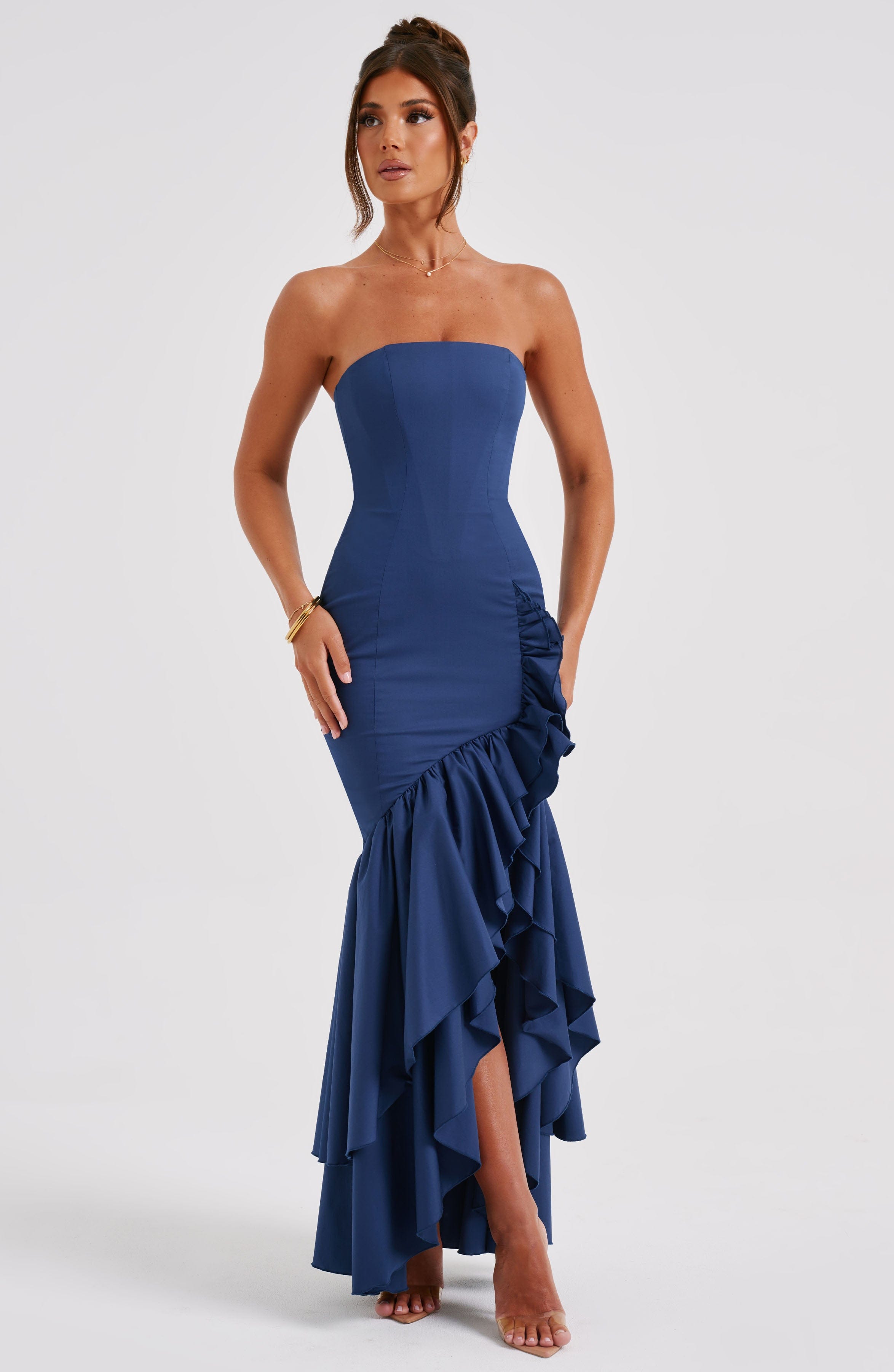 Angled view of a navy blue strapless maxi dress, emphasizing the cascading ruffles and fitted bodice.