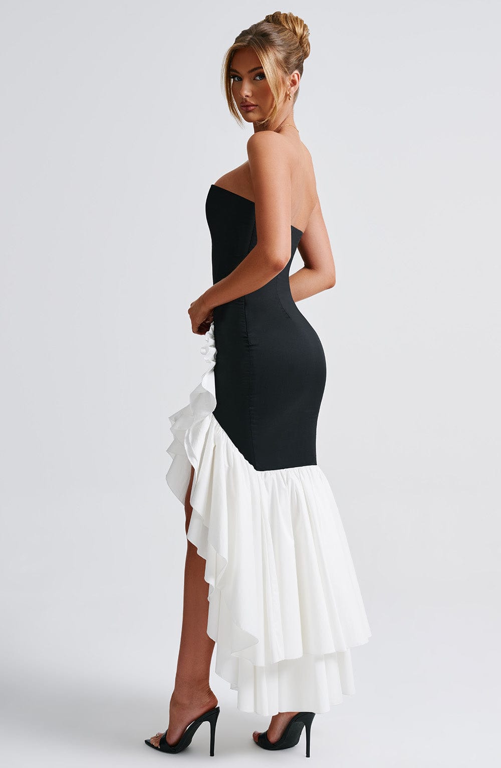 Side view of the black and white Emily Ruffle Maxi Dress, showcasing the fitted black bodice and layered white ruffle skirt.