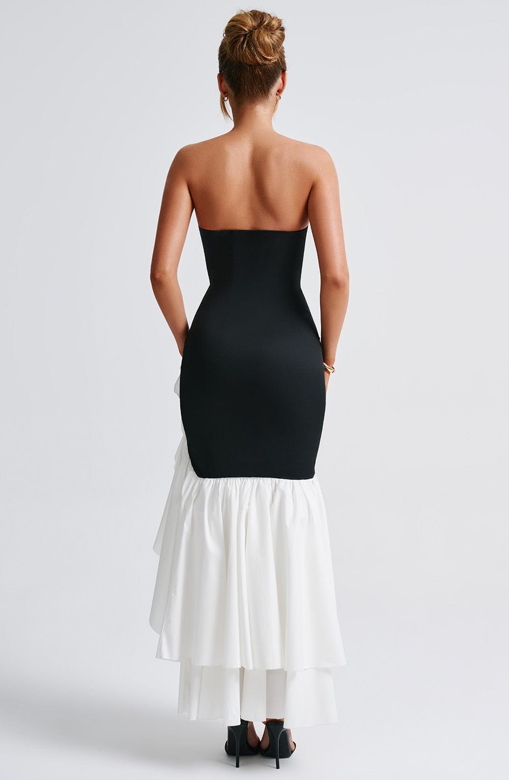 Back view of the black and white Emily Ruffle Maxi Dress, highlighting the strapless back and voluminous white ruffled train.