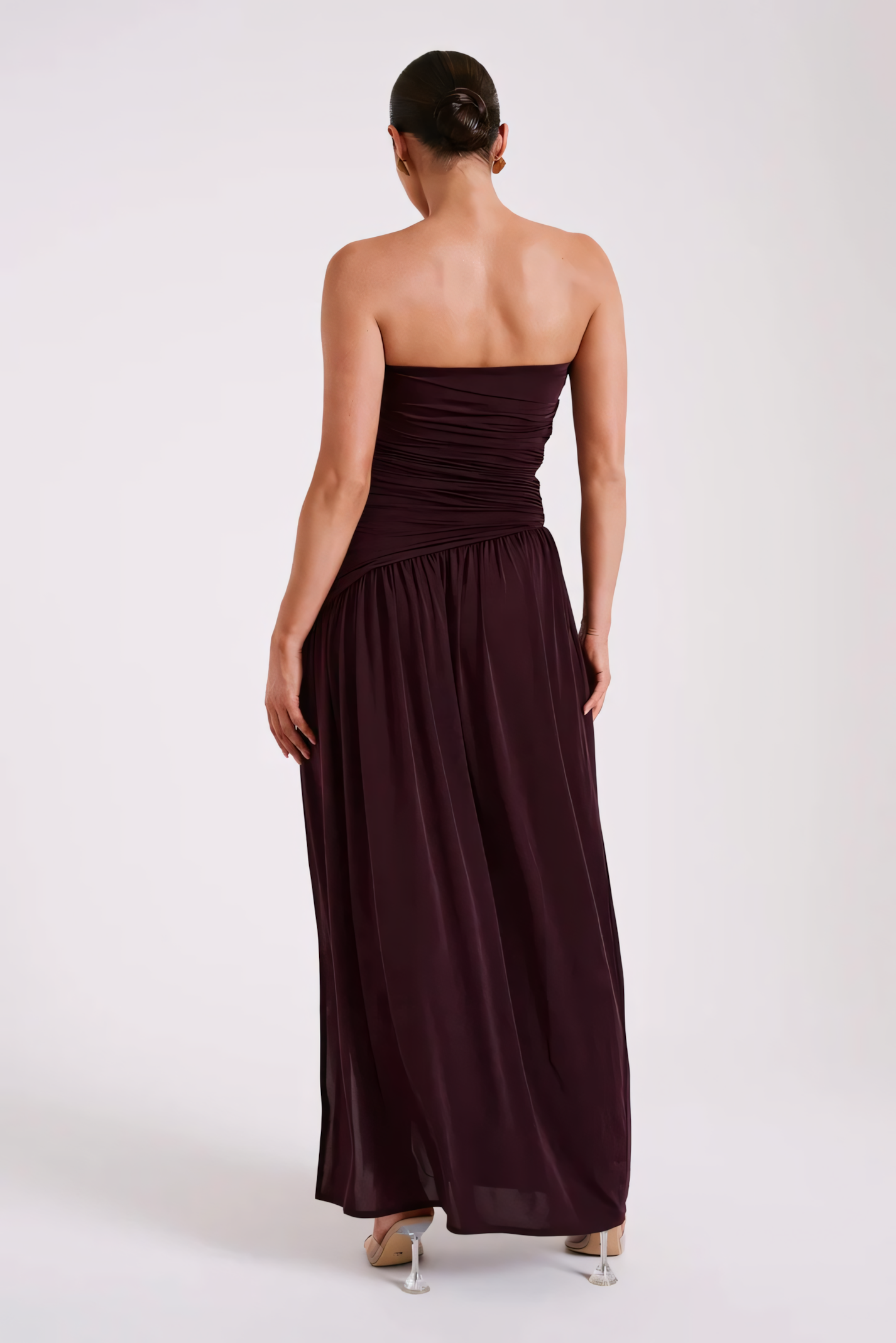 Back view of a woman in a elegant burgundy strapless maxi dress revealing the back