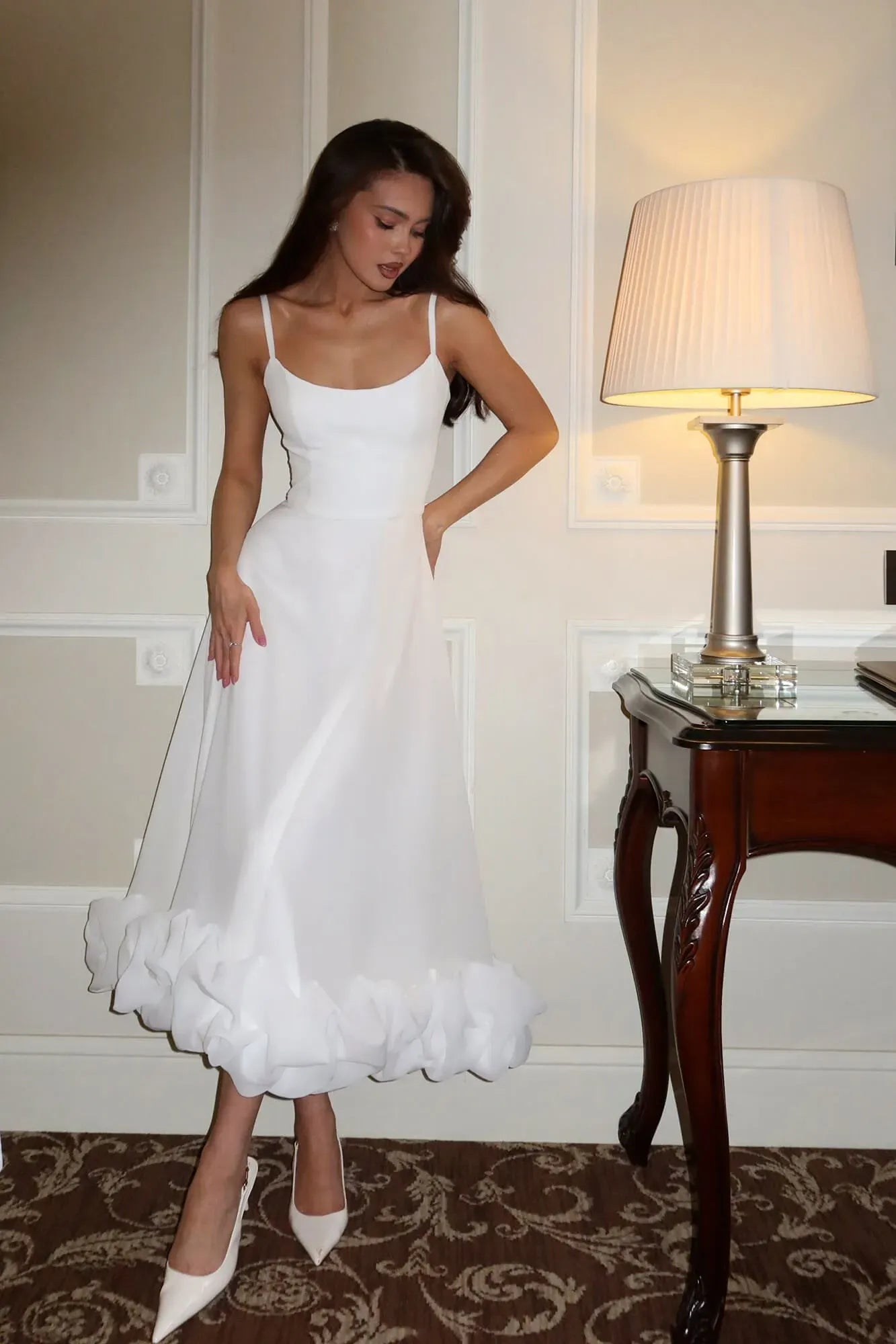 Elegant white Emmeline ruffle midi dress featuring thin straps and a unique tiered ruffle detail at the hem.