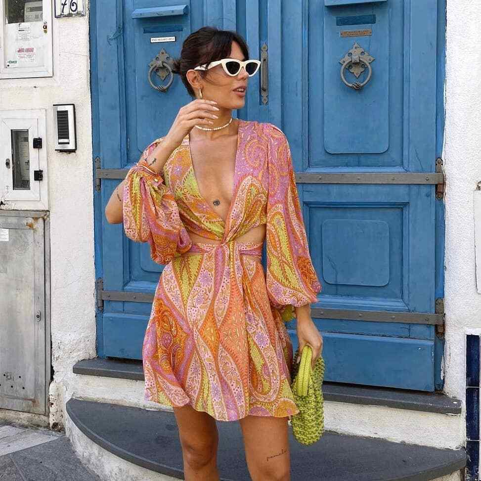 Stylish woman in sunglasses wearing a pink and orange paisley cutout mini dress standing outdoors for women