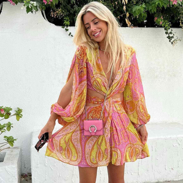 Woman in a pink, yellow, and orange paisley print mini dress with a deep V-neck and waist cutouts for women
