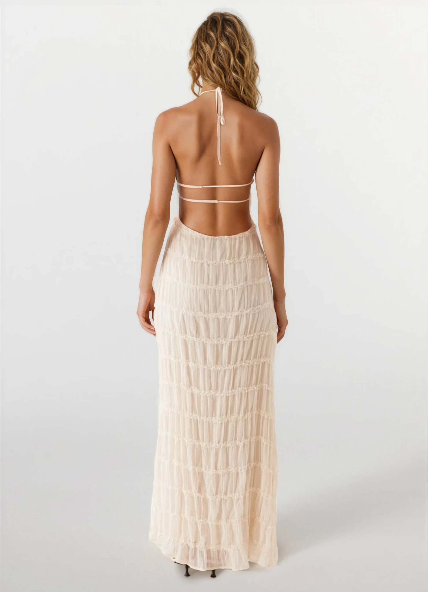 Back view of the light cream Everly textured maxi dress, showcasing the open back design with thin straps and ruched skirt.