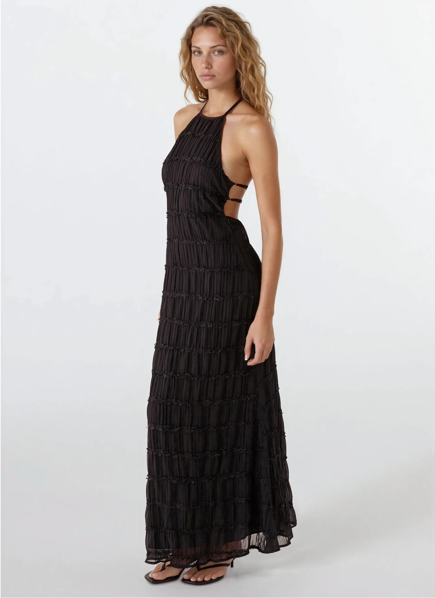 Side profile of a black Everly textured maxi dress, highlighting the halter neckline, side cutouts, and ruched fabric details.