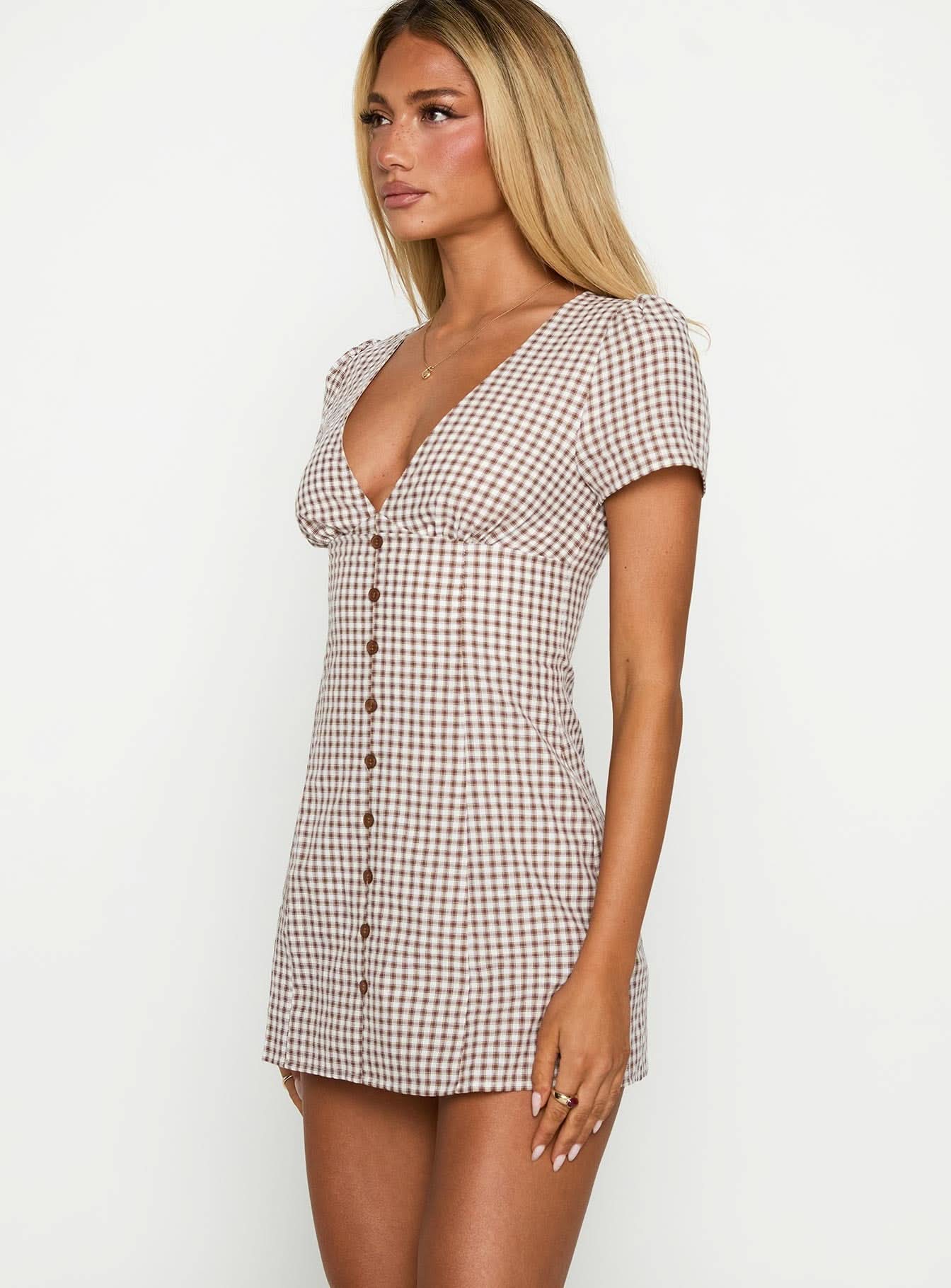 Side profile of the Fallon Check Mini Dress, featuring a brown and white gingham pattern, short sleeves, and a deep v-neckline with functional buttons.