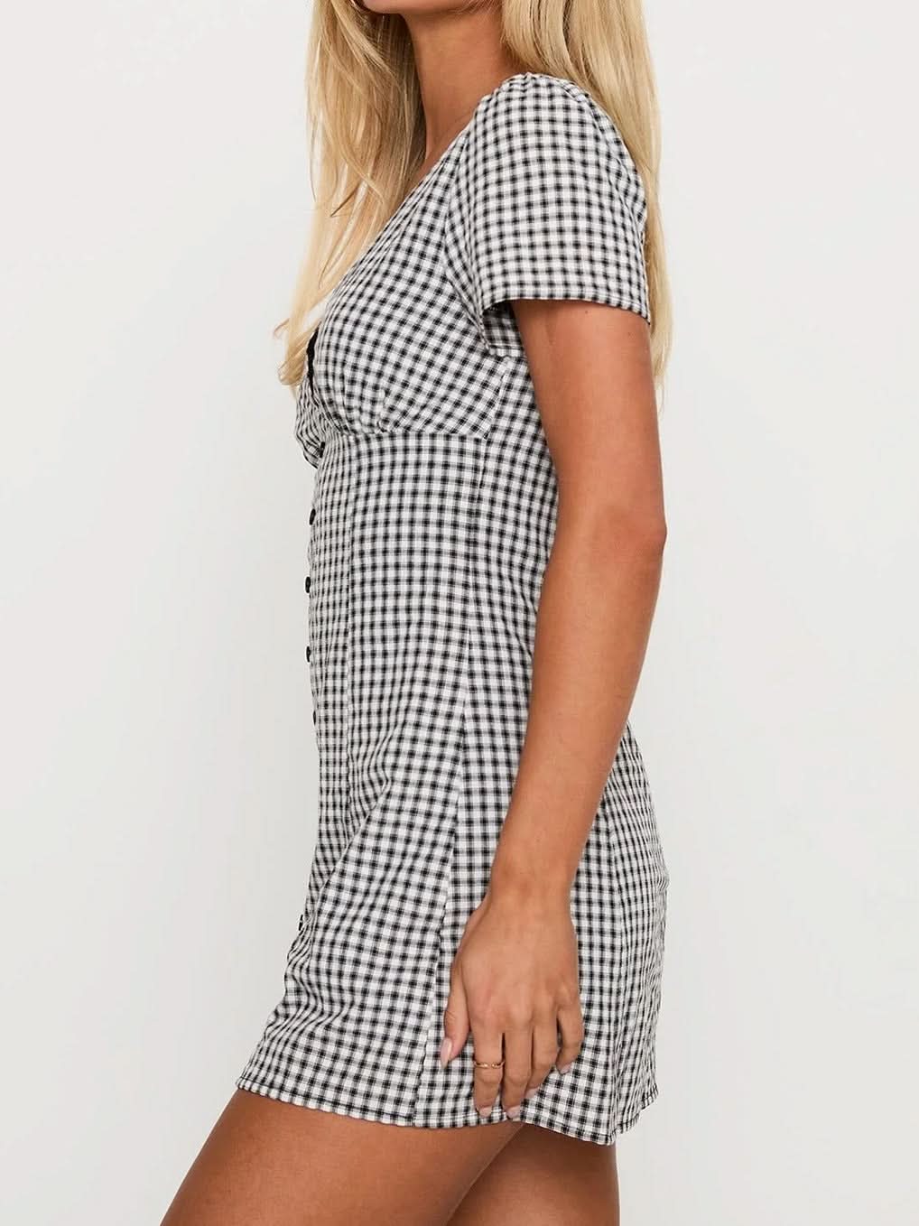Side view of the black and white gingham Fallon Check Mini Dress, showcasing the short sleeves and the fitted bodice with a button-front detail.