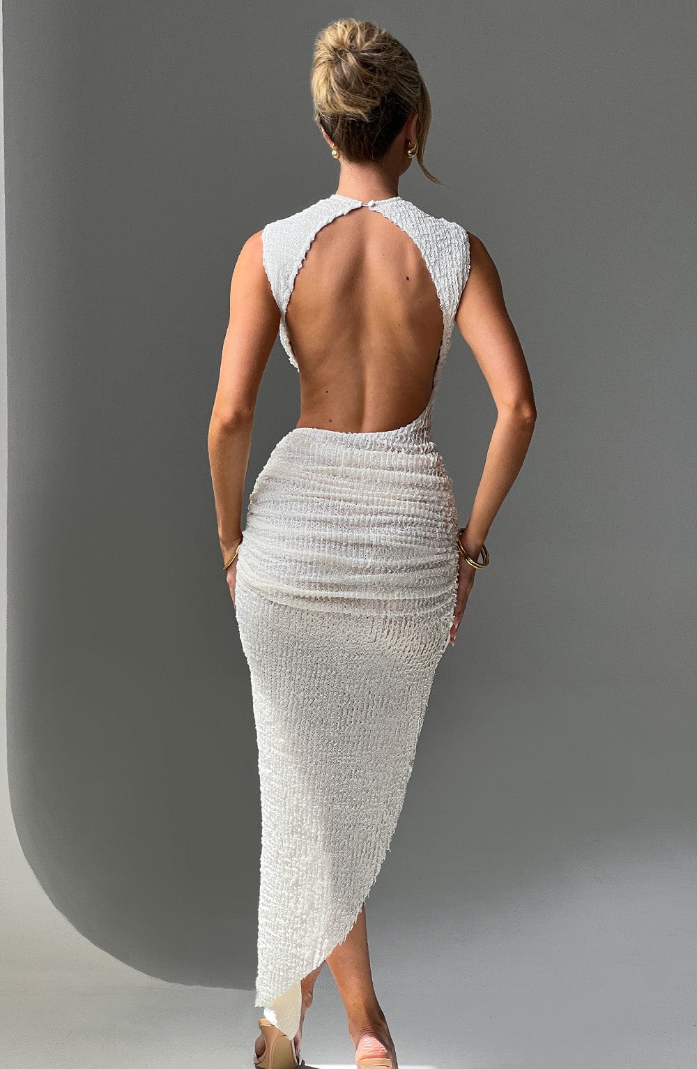 Back view of the white textured maxi dress, showcasing the open back and form-fitting silhouette.