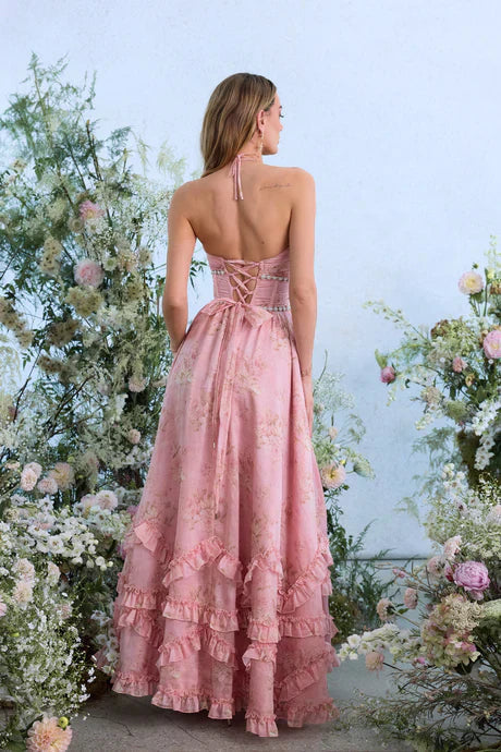 Back view of a light pink floral tiered maxi dress with halter neckline and corset back detail.